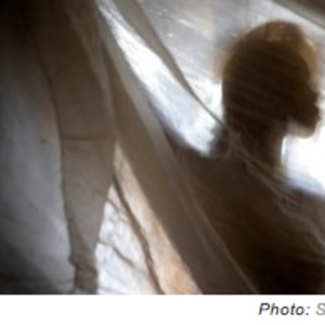 Photograph of a woman seemingly holding a sheet in front of her body